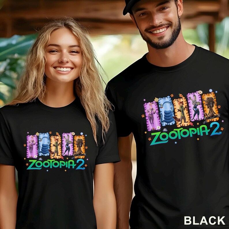 May include: Black t-shirts featuring a colorful graphic from "Zootopia 2." The design includes character illustrations and the movie title in a vibrant font. The shirts are worn by two people.