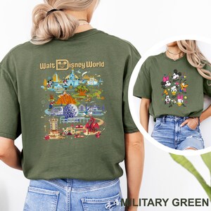 Op de afbeelding: Militairgroen t-shirt met een kleurrijke afbeelding van Walt Disney World attracties en personages. De achterkant van het shirt toont de tekst "Walt Disney World" boven een gedetailleerde illustratie van het park. Een kleinere afbeelding van Disney-personages staat op de voorkant.