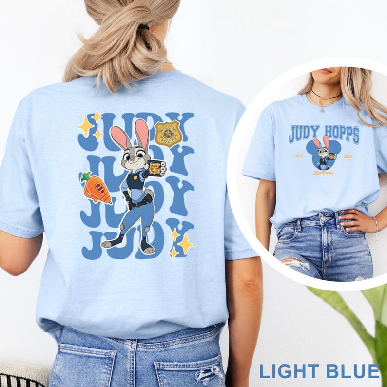 K&ouml;nnte beinhalten: Hellblaues T-Shirt mit Judy Hopps aus Zoomania. Auf der R&uuml;ckseite befindet sich eine gro&szlig;e Grafik von Judy in ihrer Polizeiuniform mit dem Text "Judy". Auf der Vorderseite steht "Judy Hopps" und ein kleines Bild von Judy.
