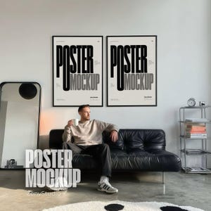 May include: Two identical vertical rectangular posters in black frames hanging on a white wall. Each poster features the bold black text "POSTER MOCKUP" in a tall, sans-serif font against a light cream background with small black text details.