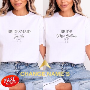 Könnte beinhalten: Weiße T-Shirts mit schwarzem Text. Eines trägt die Aufschrift "BRIDESMAID Jesika" mit einer Schleifengrafik, das andere "BRIDE Mrs. Collins" mit einer Schleifengrafik. Das Bild enthält auch den Text "CHANGE NAME'S" und einen "FAST DELIVERY"-Aufkleber.
