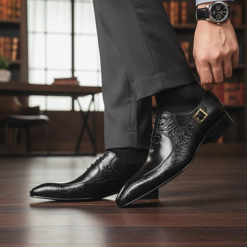 Pu&ograve; includere: Scarpe eleganti in pelle nera con dettagli floreali e a foglie in rilievo. Le scarpe presentano una punta affusolata, chiusura con lacci e fibbia color oro. Indossate con calzini neri e pantaloni grigi.