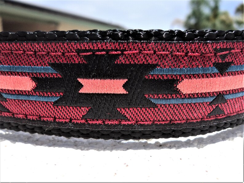 Pu&ograve; includere: Un collare per cani nero con un motivo geometrico rosso, nero e blu. Il collare &egrave; realizzato in nylon resistente e ha una fibbia in metallo robusta.
