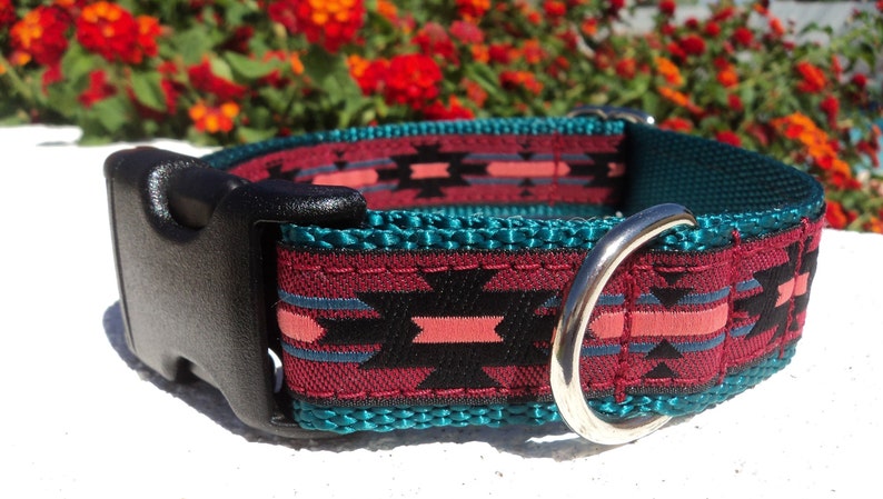 Pu&ograve; includere: Un collare per cani con motivo turchese, bordeaux, nero e rosa con una fibbia in plastica nera e un anello in metallo argentato.