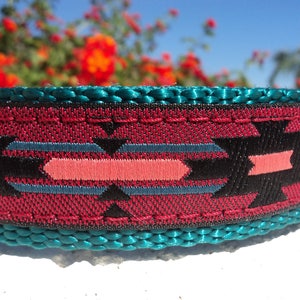 Pu&ograve; includere: Primo piano di un collare per cani in tessuto intrecciato con un motivo turchese, nero, rosa e rosso. Il collare ha un bordo cucito.