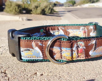 May include: A brown and green dog collar with a pattern of ducks. The collar has a silver buckle and a silver D-ring.