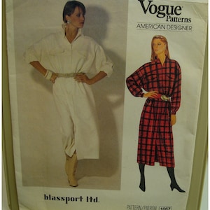 Puede incluir: Patrón de costura Vogue Patterns American Designer para un vestido. El patrón es para un vestido de manga larga con cierre de botones en la parte delantera y un cinturón. El patrón se muestra en dos modelos, uno con un vestido blanco y el otro con un vestido de cuadros rojos y negros. El número del patrón es 1067.