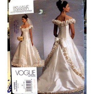 Puede incluir: Un patrón de vestido de novia vintage de Vogue, V1095, para las tallas 12-14-16. El patrón presenta un vestido de satén blanco con un escote con volantes y un lazo en la espalda.