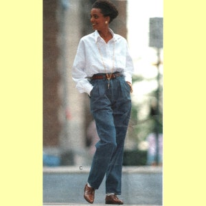 May include: A woman wearing a white button-down shirt with a gold chain necklace and a pair of high-waisted blue jeans. She is wearing brown leather shoes.