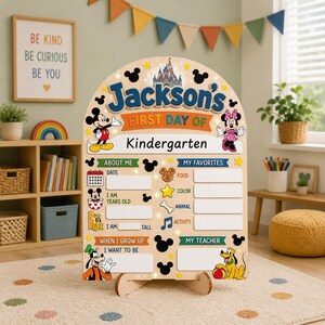May include: A light-colored wooden arched sign featuring Disney characters including Mickey Mouse, Minnie Mouse, Goofy, and Pluto. The sign displays the text Jackson's First Day of Kindergarten with blank fields for personal details and favorites.