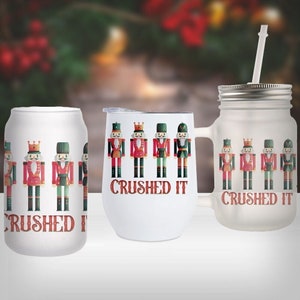 May include: Three white tumblers with a Christmas nutcracker design and the text "Crushed It". The tumblers are a standard size, a wine glass size, and a mason jar size.