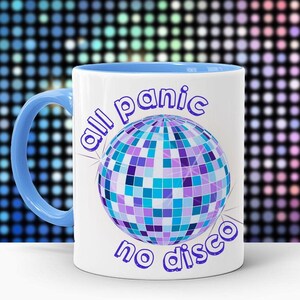 May include: White ceramic mug with a blue rim. The mug has a disco ball graphic and the text "all panic no disco" in purple.