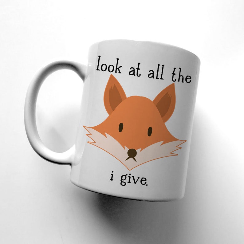 May include: White ceramic mug with a fox illustration and the text "look at all the i give."