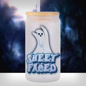May include: A white frosted glass tumbler with a bamboo lid and a straw. The tumbler has a cartoon ghost with a blue outline and the text "SHEET FACED" in blue and purple letters.