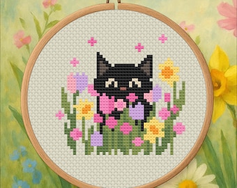 May include: A cross-stitch embroidery of a black cat surrounded by colorful flowers, including pink, yellow, and purple blooms. The cat has a pink bow and is set in a wooden embroidery hoop. The background is a soft, painted floral scene.