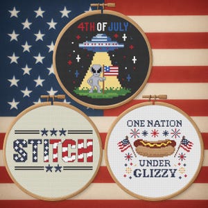 Puede incluir: Tres aros de punto de cruz con temas patrióticos. Uno presenta un OVNI, un extraterrestre y el texto "4TH OF JULY". Otro dice "STITCH" en rojo, blanco y azul. El tercero dice "ONE NATION UNDER GLIZZY" con un perrito caliente y banderas.