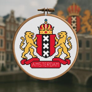 Puede incluir: Un bastidor de bordado de punto de cruz con el escudo de armas de Ámsterdam. El diseño incluye un escudo rojo con tres cruces negras, una corona dorada y dos leones dorados. La palabra "AMSTERDAM" se muestra en una pancarta roja.