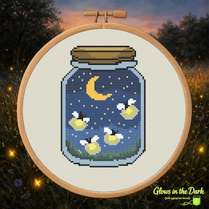 Può includere: Ricamo a punto croce in un telaio di legno. Il disegno presenta un barattolo pieno di cielo notturno, una luna crescente, stelle e lucciole luminose. Il testo "Glows in the Dark" è in basso.