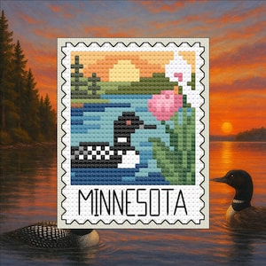 Può includere: Un disegno a punto croce di un colimbo su un lago, con uno sfondo di tramonto. Il disegno è a forma di francobollo con la scritta "MINNESOTA" in basso. Fiori rosa e bianchi sono sul lato destro del francobollo.