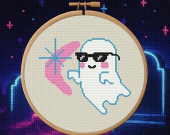 Pode incluir: Bordado em ponto cruz num arco de madeira com um fantasma branco a usar óculos de sol e um bumerangue rosa. O fantasma tem um contorno azul claro e bochechas cor-de-rosa. O fundo é azul escuro com cruzes rosa e azuis néon.