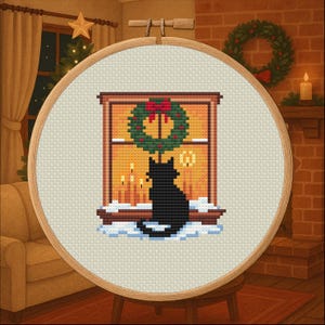 May include: Cross-stitch embroidery in a wooden hoop. The design features a black cat silhouetted against a window with a Christmas wreath and lit candles. The background shows a cozy room with a Christmas tree and fireplace.