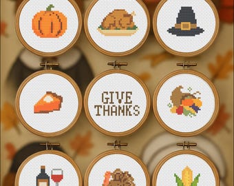May include: A collection of nine cross-stitch embroidery hoops with Thanksgiving-themed designs. The designs include a pumpkin, turkey, pilgrim hat, pie, the words "GIVE THANKS", cornucopia, wine, turkey, and corn. The hoops are set against a blurred background.