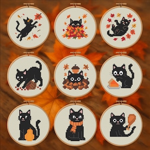 May include: Nine cross-stitch embroidery hoops featuring black cats in various autumn scenes. The cats are surrounded by fall leaves, pumpkins, and acorns. Each design is framed in a wooden hoop, creating a cozy, seasonal theme.