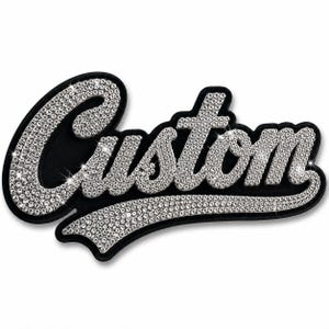 Könnte beinhalten: Ein schwarzer Aufnäher mit dem Wort Custom in einer kursiven Schriftart. Die Buchstaben sind mit zahlreichen kleinen, klaren, reflektierenden Strasssteinen gefüllt, die einen funkelnden Effekt auf dem dunklen Hintergrund des Stoffaufnähers erzeugen.