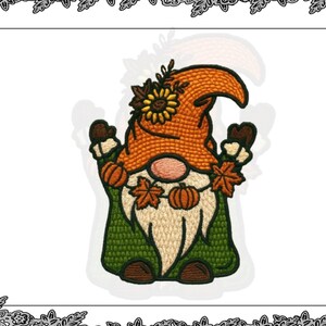 Può includere: Design di gnomo ricamato con cappello arancione, cappotto verde e lunga barba bianca. Lo gnomo tiene in mano zucche e foglie autunnali. Un girasole adorna il cappello. Il design è incorniciato da un bordo decorativo.