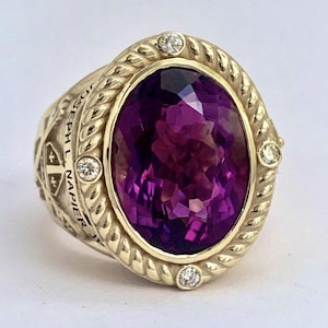 May include: A gold ring featuring a large, oval-cut purple amethyst stone at the centre. The stone is surrounded by a twisted rope-style gold border accented with four small round diamonds. The side of the ring is engraved with the text JOSEPH L. NAPIER.