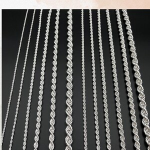 May include: A collection of silver-colored chain necklaces in various styles and thicknesses against a black background. The chains are displayed vertically, showcasing different rope and link designs. Text at the top reads, "For different custom chain options, please feel free to contact us."