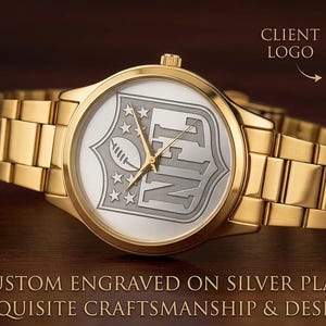 Puede incluir: Un reloj de pulsera dorado con una esfera plateada con el logotipo de la NFL. El reloj tiene una correa y agujas doradas, con el logotipo de la NFL grabado en la esfera. La imagen tambi&eacute;n incluye un logotipo de la NFL.