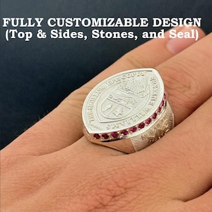 May include: A silver ring with a large oval face, featuring an engraved crest and the text "THE SIGILLUM EPISCOPUS". The ring is adorned with small, red gemstones around the face. The text "FULLY CUSTOMIZABLE DESIGN" is at the top.