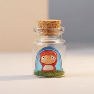 Puede incluir: Una peque&ntilde;a botella de vidrio transparente con tap&oacute;n de corcho. En el interior, una figura en miniatura de un personaje de dibujos animados con pelo rojo y un atuendo rojo est&aacute; encerrada en una c&uacute;pula azul, sobre un c&eacute;sped verde.