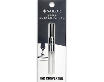 May include: A clear ink converter for fountain pens, packaged on a black and white card. The card features the brand name "SAILOR" and Japanese text. The words "INK CONVERTER" are printed at the bottom.