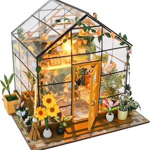 May include: Miniature greenhouse model with glass walls and a pitched roof. The interior is filled with tiny plants, flowers, and furniture. The open door reveals a glimpse of the interior, illuminated by a warm light. Decorative vines and flowers adorn the exterior.