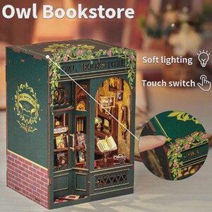 K&ouml;nnte beinhalten: Miniaturmodell der Owl Bookstore mit gr&uuml;nem &Auml;u&szlig;eren, Backsteinfassade und floralen Akzenten. Das Modell verf&uuml;gt &uuml;ber Innendetails wie B&uuml;cherregale, B&uuml;cher und sanfte Beleuchtung. Der Text "Owl Bookstore" ist auf der Ober- und Seite sichtbar.