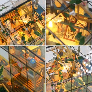 May include: A miniature greenhouse model with glass walls and a wooden frame. Inside, there are shelves with potted plants, miniature furniture, and decorative items. The scene is illuminated by small lights, creating a warm, inviting atmosphere. The model includes a butterfly picture.