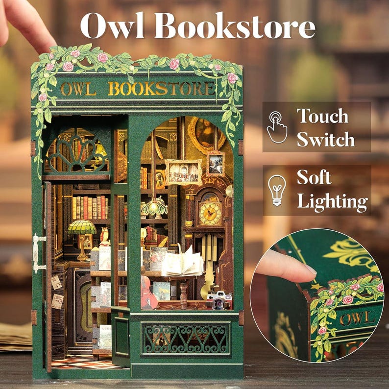 K&ouml;nnte beinhalten: Miniaturmodell der Owl Bookstore mit gr&uuml;ner Fassade, floralen Akzenten und dem Schriftzug "Owl Bookstore". Das Innere zeigt B&uuml;cherregale, eine Uhr und sanfte Beleuchtung, mit einem Touch-Schalter.