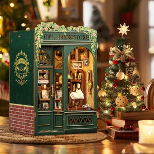 May include: A miniature green wooden Owl Bookstore model with a red brick base, adorned with floral accents and the text "OWL BOOKSTORE." A Christmas tree with ornaments and lights is in the background.