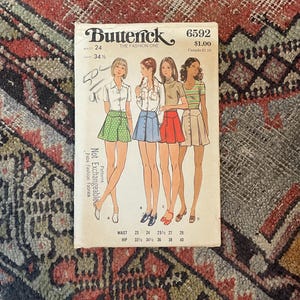 May include: A Butterick 6592 sewing pattern envelope featuring illustrations of four figures wearing button-front skirts in green polka dot, blue, red, and beige. The cover displays waist and hip measurements in inches and the text Not Exchangeable.
