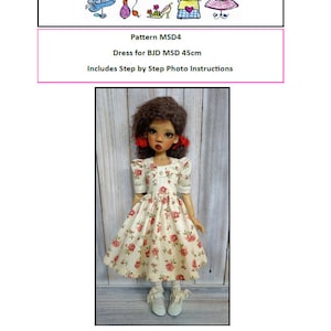 May include: A doll wearing a white dress with a floral pattern and a pink bow in her hair. The dress is 45 cm long and is designed for a MSD doll. The image includes the text "Trentsation by Marsha Trent" and "Pattern MSD4".