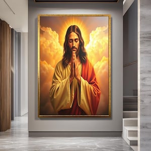 May include: A framed religious artwork depicts a figure with long brown hair, wearing a yellow and red robe, with hands clasped in prayer. The background features a golden halo and clouds, with a gold-colored frame.