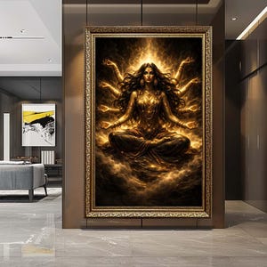Op de afbeelding: Een ingelijst kunstwerk dat een veelarmige godheid in een meditatieve pose toont, die gouden licht uitstraalt. Het kunstwerk heeft ingewikkelde details, een rijk kleurenpalet van goud en bruin en is gevat in een decoratieve gouden lijst. Het kunstwerk wordt in een modern interieur getoond.