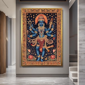 Op de afbeelding: Een ingelijst kunstwerk dat een blauwe godheid met meerdere armen afbeeldt, versierd met gouden sieraden en een rode rok. De achtergrond is donkerblauw met gouden stippen en bloemmotieven. De lijst is goudkleurig.