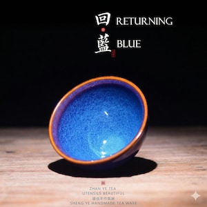 May include: A small, blue ceramic tea bowl with a textured interior and a dark brown rim. The bowl is set against a dark background, with the words "RETURNING BLUE" in white text above it. The bottom of the image has text in Chinese.