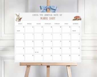 May include: A white calendar on a wooden easel, featuring the text "Guess the Arrival Date of Marie Baby." The calendar has a grid for tracking dates, with illustrations of a rabbit and a mushroom. A light blue bow is tied at the top.