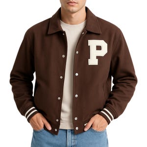 May include: A brown varsity jacket with a white "P" patch on the chest. The jacket has a button-up front, a collar, and white stripes on the cuffs. The jacket is worn over a light-colored t-shirt and blue jeans.