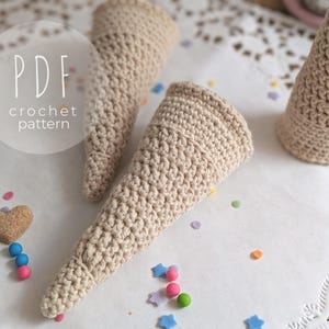 Könnte beinhalten: Nahaufnahme von mehreren beigefarbenen Häkelkegeln, möglicherweise für ein Bastelprojekt. Das Bild enthält den Text "PDF crochet pattern". Buntes Konfetti ist um die Kegel herum verstreut.