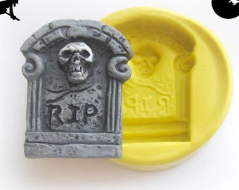 Puede incluir: Una lápida gris con una calavera y las letras "RIP" junto a un molde amarillo. La lápida está detallada con una calavera y elementos decorativos. El molde tiene la forma de la lápida. Temática de Halloween.